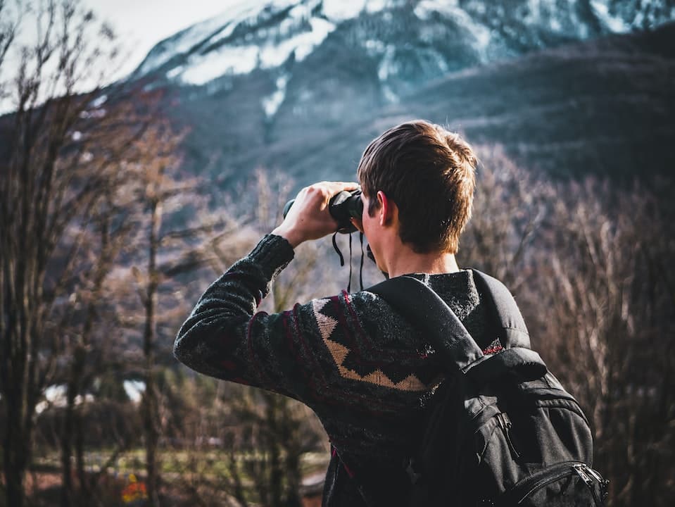 Man Using Black Binoculars Near Forest Trees at Daytime